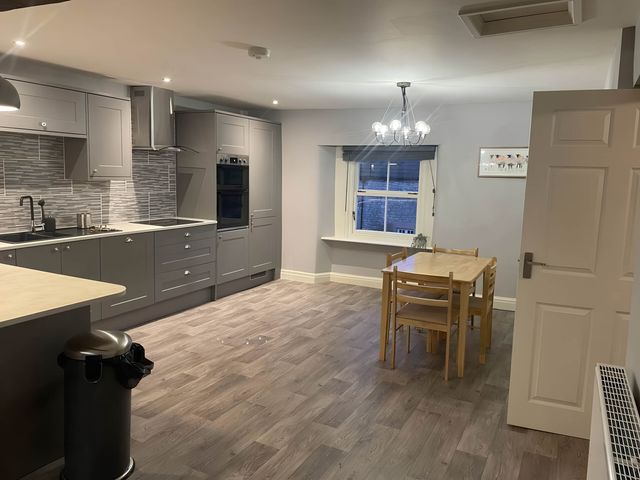 A kitchen with cabinets and a dining table at Cosy Apartment above Village Pub