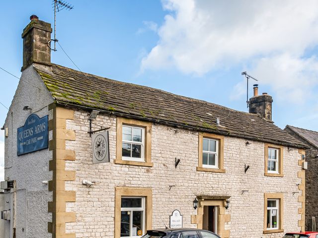 A pub building with a sign and a car outside at Queens Arms in Taddington