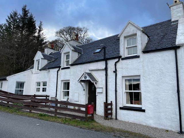 A cottage with a front door and windows at 1 Keepers Cottage, Skeabost Bridge, Isle Of Skye