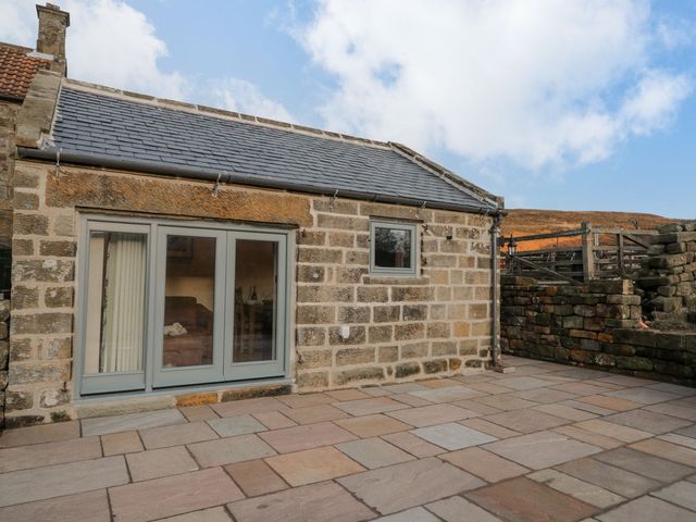An outdoor view of a stone building with sliding doors and patio at Little Esklets in Whitby