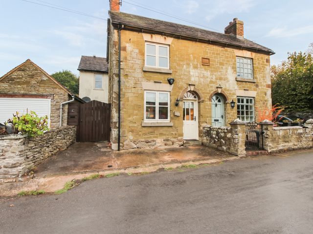 An exterior view of a house with stone walls and a gate at Stone Cottage in Church Stretton