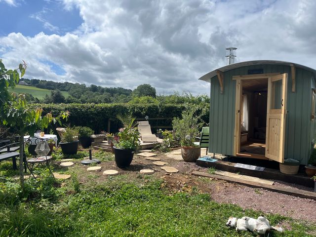 A garden with a hut, seating area, and planters at Shepherd Hut Gloucester