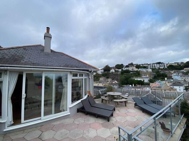 An outdoor area with deck chairs and a table at 4 Bed House-Sleeps 8-Parking-Pets-MarinaSeaView in Torquay