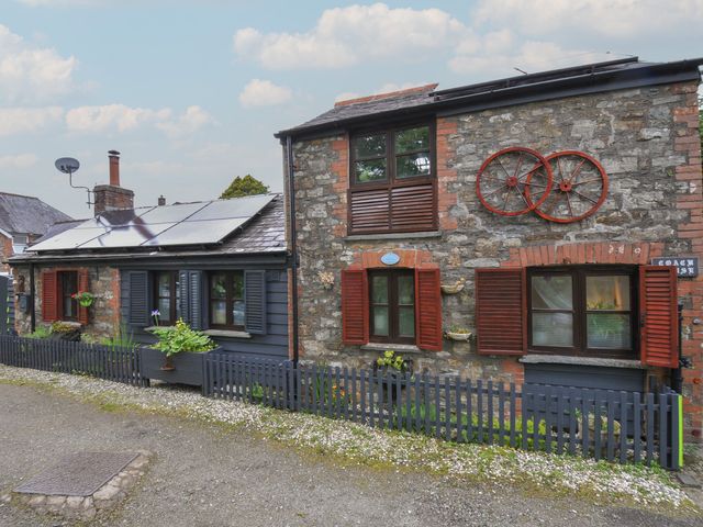 An outdoor view of a stone building with windows and shutters at Coach House in Camelford