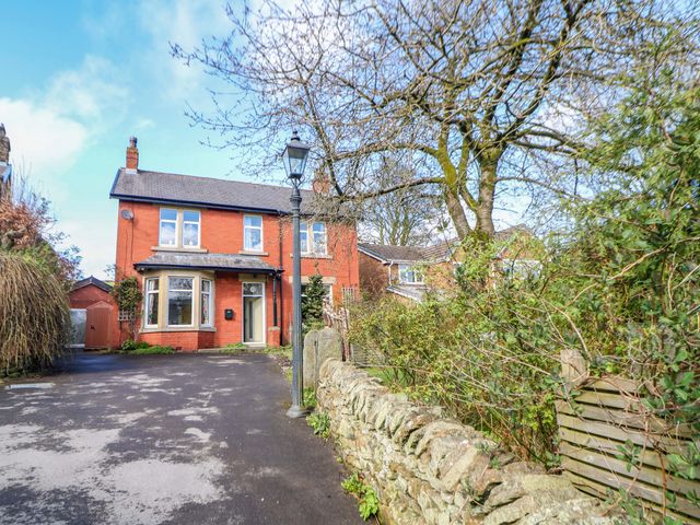A house with a garden and stone wall at Glenside Lodge in Chapel-En-Le-Frith