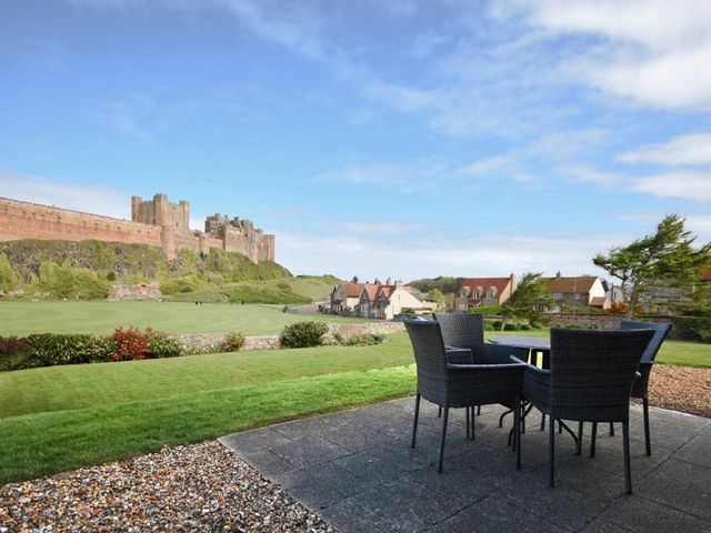 A garden with a table and chairs overlooking a castle at Northrawe Bamburgh