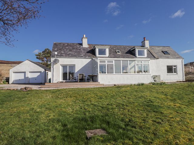 A house with a garage and grass area at An Grianan in Kinlochbervie