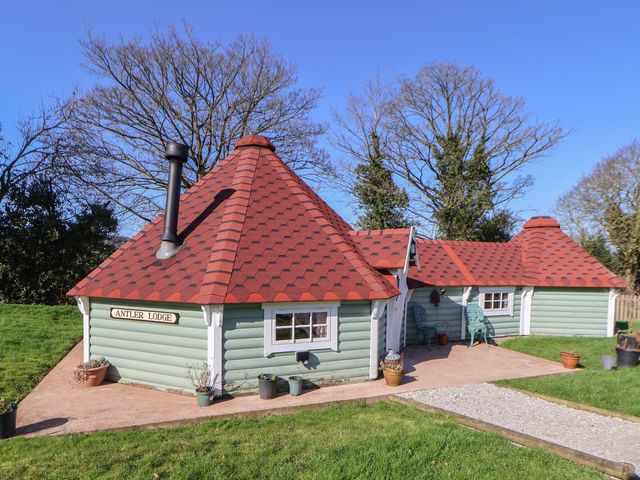 An outdoor view of a log cabin with a chimney at Antlers Lodge in Biddulph Moor