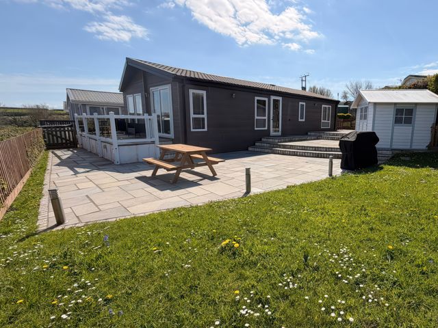 A patio area with a table and chairs at Wernlas Lodge in Oxwich