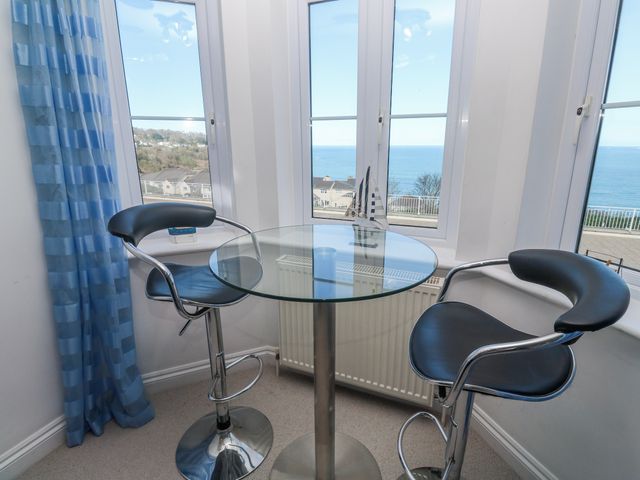 A dining area with a glass table and bar stools at 21 Compass Point Carbis Bay