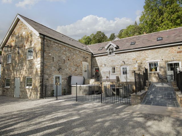 An outdoor view of a stone building with a fence and steps at Sun Trevor Barns 3, Llangollen