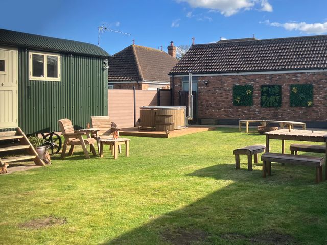 A garden with a shepherd hut and hot tub at Twit Twoo Shepherds Hut North Somercotes