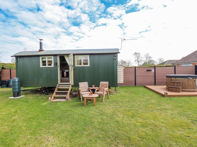 A shepherd hut with outdoor seating and a hot tub at Twit Twoo Shepherds Hut North Somercotes