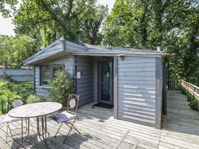 An outdoor view of a house with a table and chairs at Hedgehogs Lodge South Molton