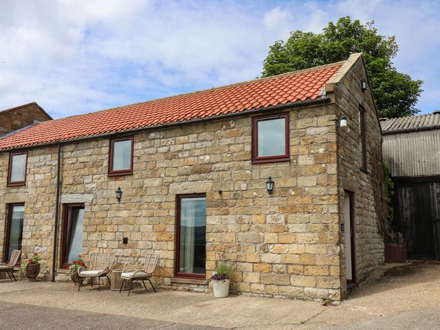 A stone building with windows and outdoor seating at Swallow Cottage in Lealholm