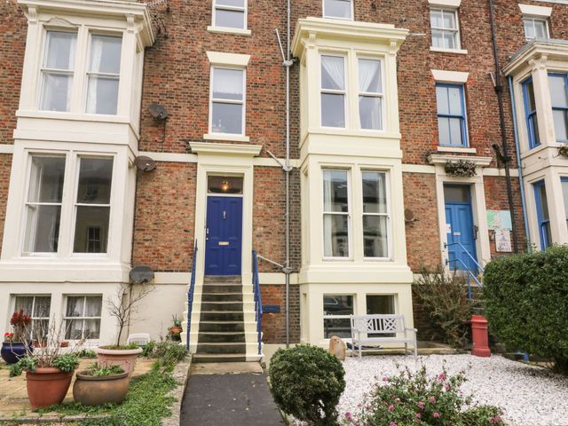 A building facade with a blue front door and planters at The Hideaway in Whitby