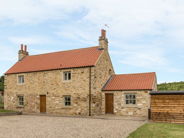 A stone house with a red roof and gravel yard at Orchard Cottage in Durham
