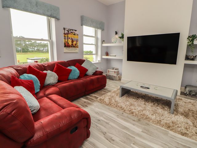 A living room with a sofa and television at Sugar Loft in Silloth