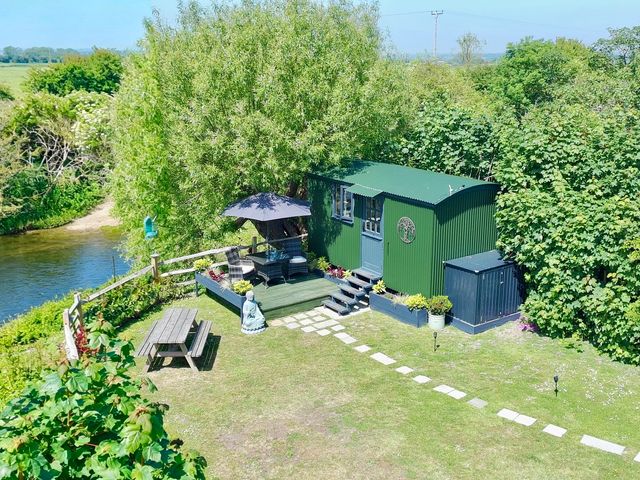A garden with a shepherd's hut, seating area, and plants at Salthaven Shepherds Hut Pevensey Bay
