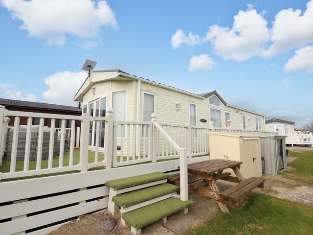 A mobile home with a deck and table at Pemberton Knightsbridge in Morfa Bychan