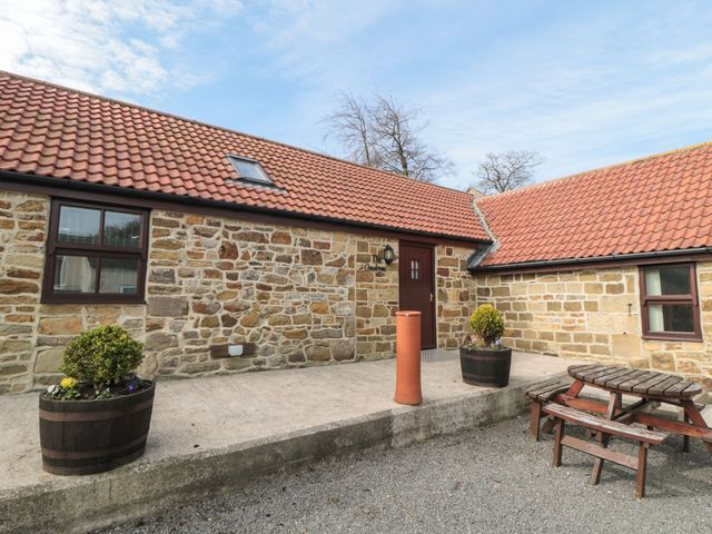 An outdoor area with a stone building and planters at The Cow Byre in Lingdale
