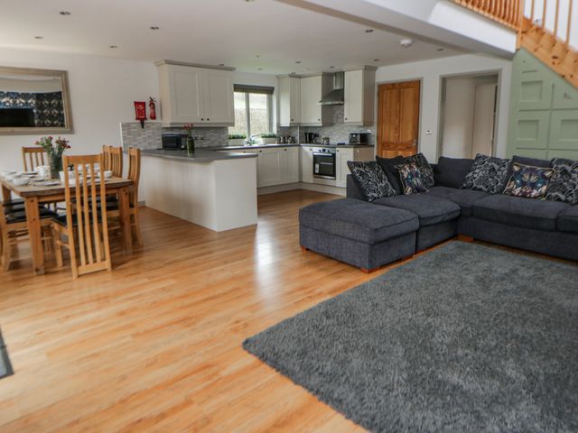 A living room with a sofa and dining area at Maple Lodge in Knighton