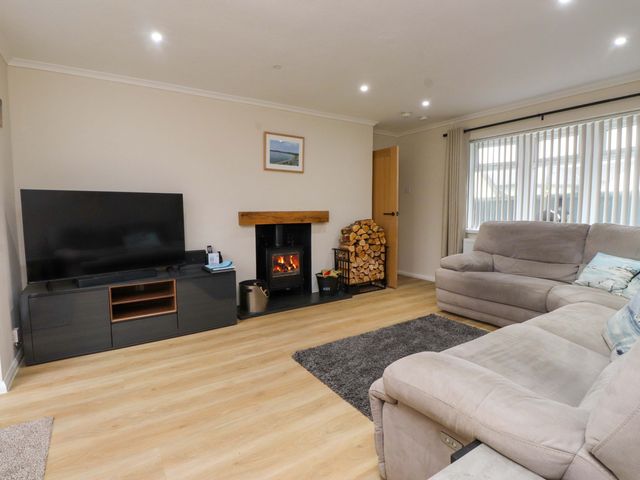 A living room with a television and fireplace at Y Byngalo in Trearddur Bay