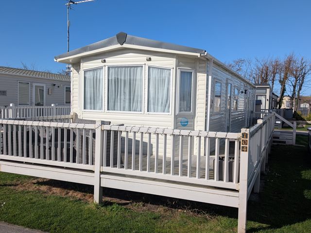 A mobile home with a deck and fence at 104 Lido Beach in Prestatyn