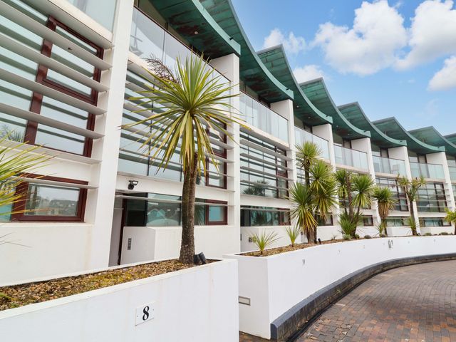 An exterior view of a modern building with palm trees at 12 Nautilus in Westward Ho!