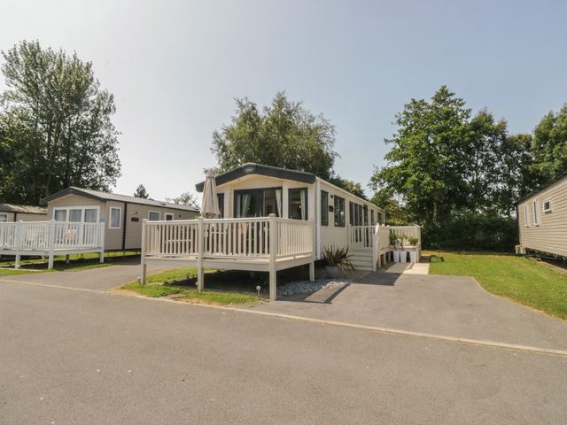 A static caravan with a deck and garden area at Hedgerow Lodge Haven Lakeside near Grange-Over-Sands