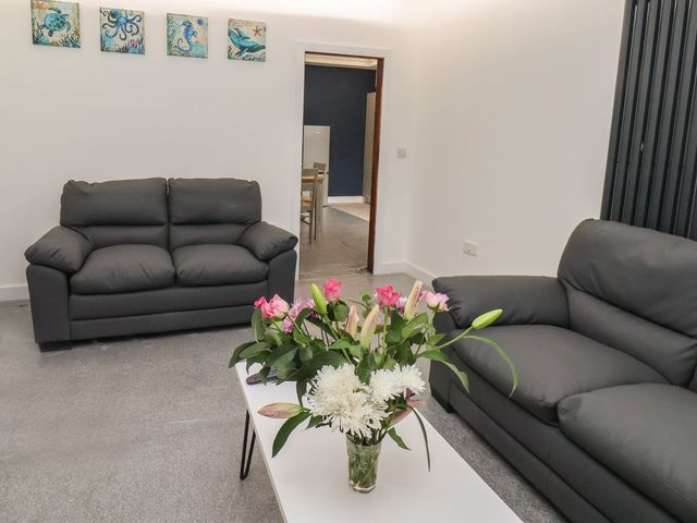 A living room with two sofas and a table with flowers at Frankie’s Seaview 2 in Bridlington