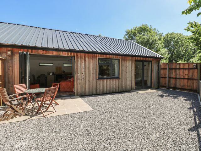 An outdoor area with a wooden building and a table with chairs at Brookview Goldfinch in Haverfordwest