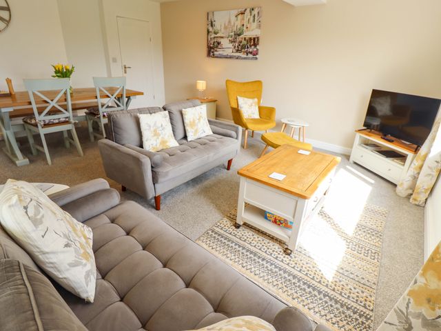 A living room with a sofa, armchair, coffee table, and television at Field View in North Walsham