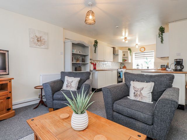 A living room with a coffee table and kitchen area at Hen Fecws in Rhoshirwaun near Sarn Meyllteyrn