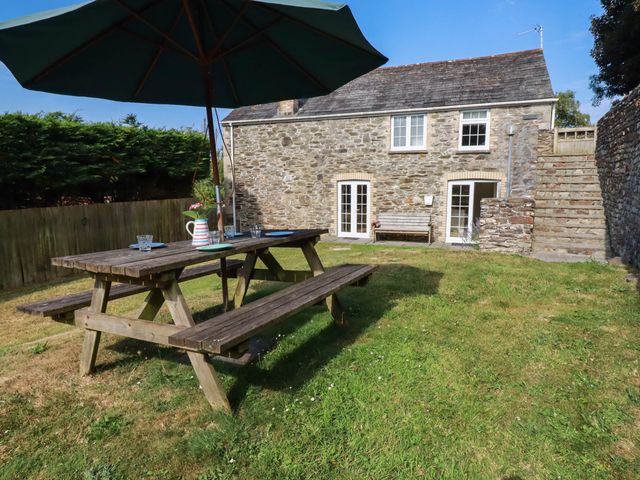 A garden with a picnic table and stone house at Bryher Cottage in St Mawgan