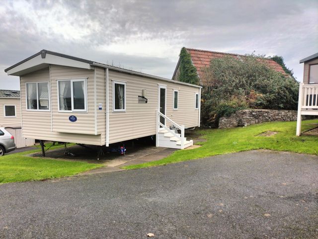 A caravan with stairs on a grass area at Beverley Bay Holiday Park - Holiday Accommodation 333 Paignton