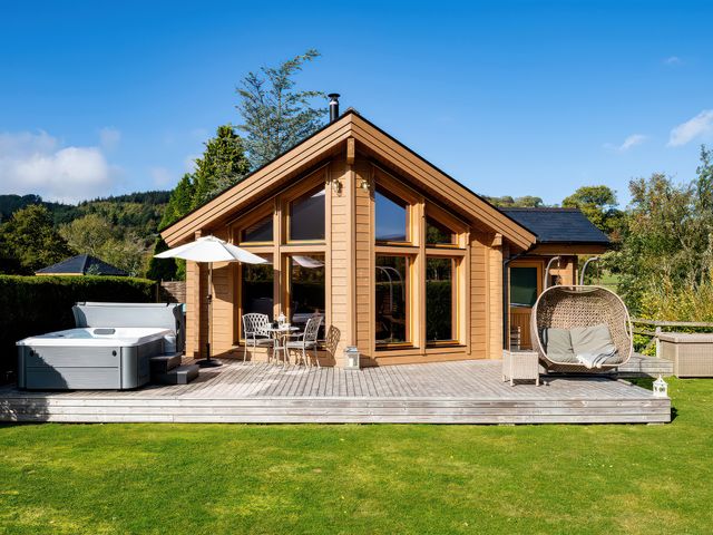 A garden with a hot tub and outdoor seating at Gezellig Log Cabin in Llandrillo