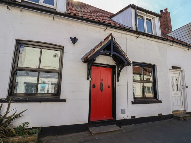A house exterior with a red front door and windows at Fleming Cottage
