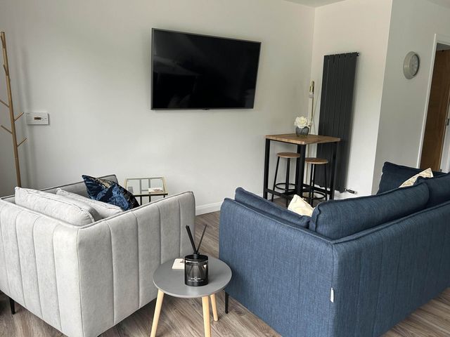 A living room with sofas, a television and a bar table at Stylish NC500 base with panoramic views Inverness