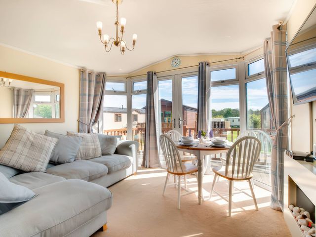 A living room with sofa and dining table at Pet-friendly lodge with hot tub near the coast
