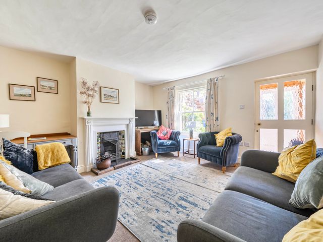 A living room with a sofa and armchairs near a fireplace at Coastal cottage near harbour, beach and pubs in Brancaster