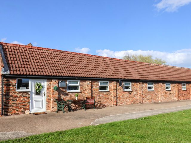 A brick exterior of a building with a pathway and bench at Lamb Cottage Stockton-On-Tees