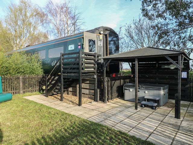 An outdoor area with a train, stairs, and hot tub at Paddington Railway Carriage 2 with hot tub Ely
