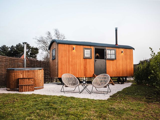 A wooden cabin with hot tub and chairs outside at Shepherds View in Bradley near Ashbourne