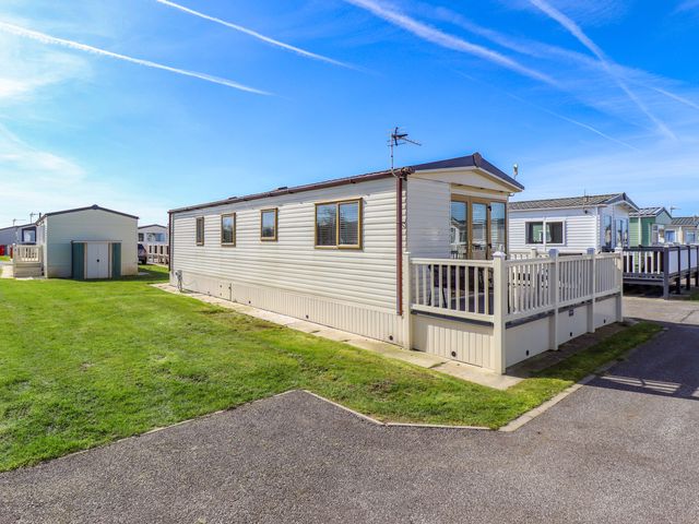 A mobile home with a deck and shed at Loopy’s Place - PG178 in Chapel St Leonards