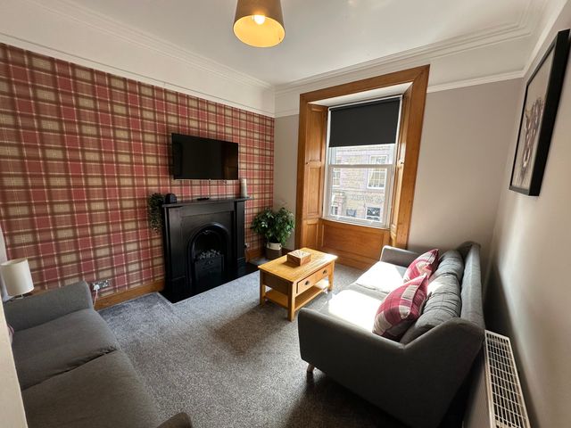 A living room with a television and a fireplace at The Tweed in Melrose