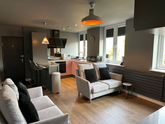 A living room with a sofa and kitchen area at The Tay in Melrose