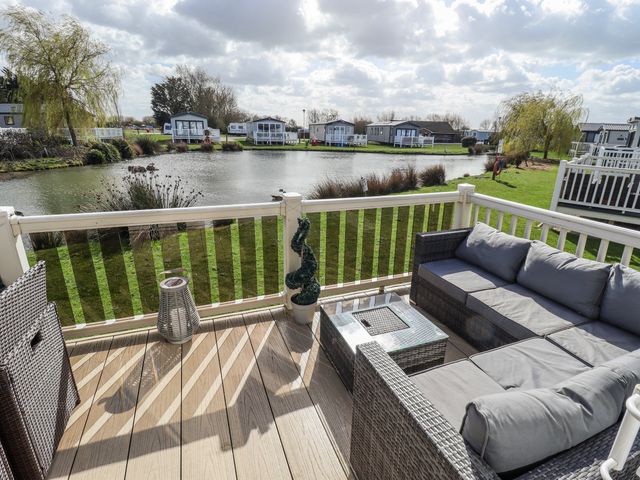 An outdoor area with a sofa and coffee table overlooking a pond at 13 The Lakes Mablethorpe