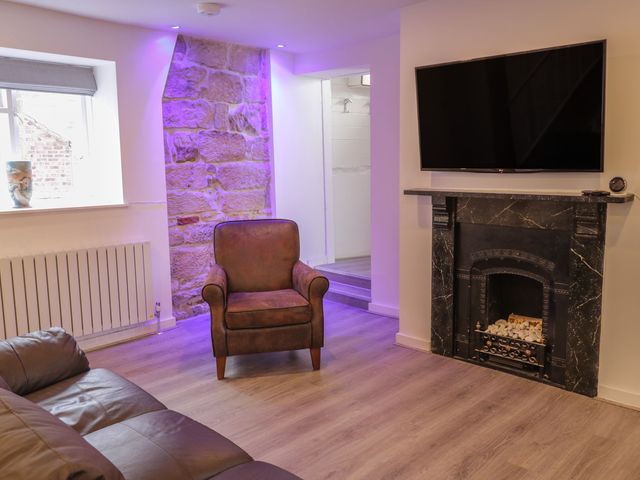 A living room with an armchair and television at 47A Baxtergate in Whitby