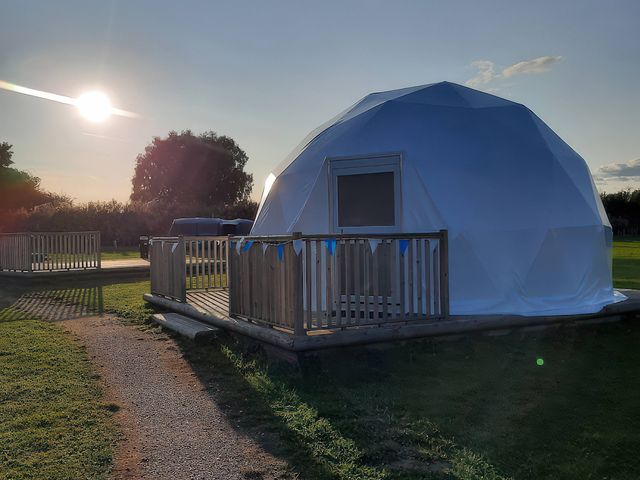 A geodesic dome with a deck on a grassy area at Sherwood - Geodome in Mansfield